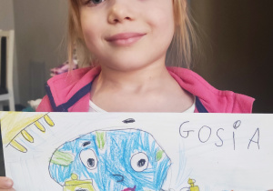 Dziewczynka trzyma swój rysunek